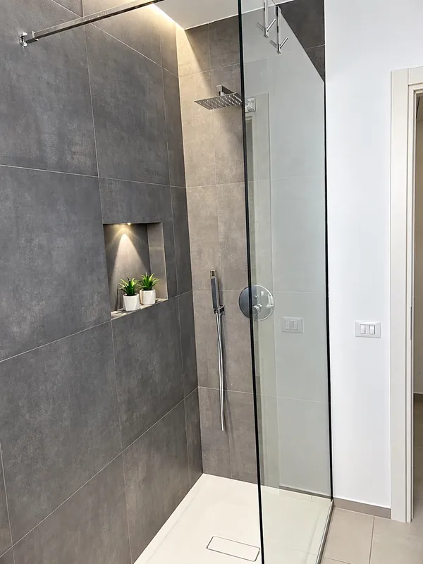 La doccia walk-in in vetro dell'appartamento, con la nicchia illuminata