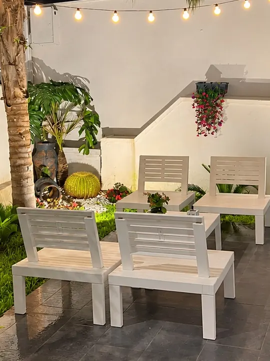 L'angolo relax del giardino di sera, con le sedute bianche e le lanterne