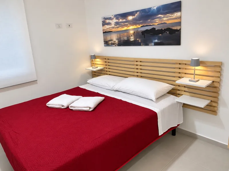 La seconda camera dell'appartamento vista di lato, con il letto matrimoniale e la testiera in legno a doghe