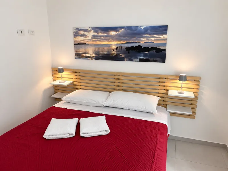 La seconda camera dell'appartamento vista di fronte, con le lampade sulle mensole e il quadro del mare